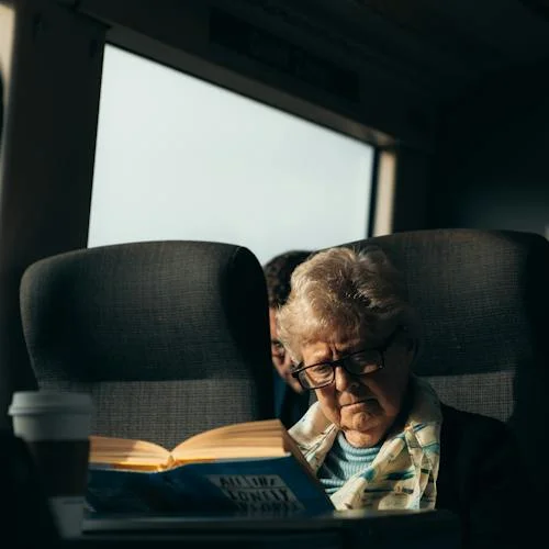Elderly Woman Reading Book in Train